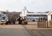 農業近代化施設の外観の写真。フォークリフトでトラックに荷物を積んでいる様子が見える。
