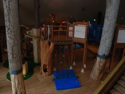 フローリングの床の上に木でできた滑り台や木でできた梯子のような遊具が設置してあるつべつ木材工芸館キノスの内装の写真