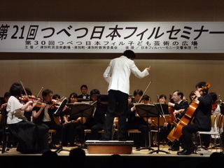 「第21回つべつ日本フィルセミナー」指揮者が指揮をし、様々な楽器を演奏している人々の写真