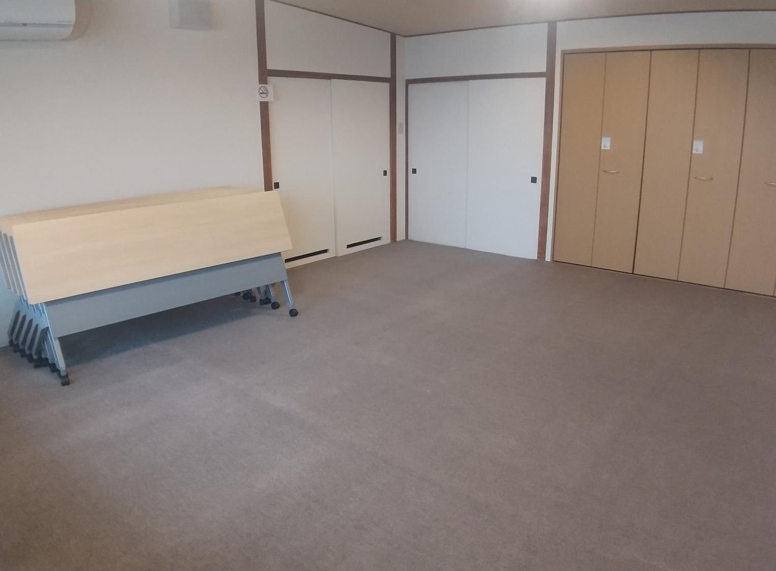 床にカーペットが敷いてあり、奥には机がたたんでおいてある第2和室の写真