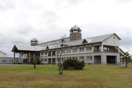 広々とした敷地の奥に、2階建てで三角屋根、横長の建物の津別中学校の外観写真