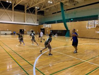 体育館の中で、講師と子ども達がバスケットボールでゲームをしている様子の写真