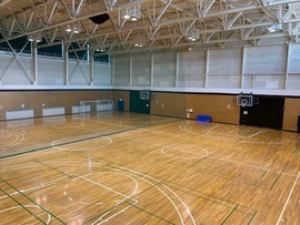 広々として天井が高く壁にはバスケットゴールが設置された農業者トレーニングセンター内アリーナの内観写真